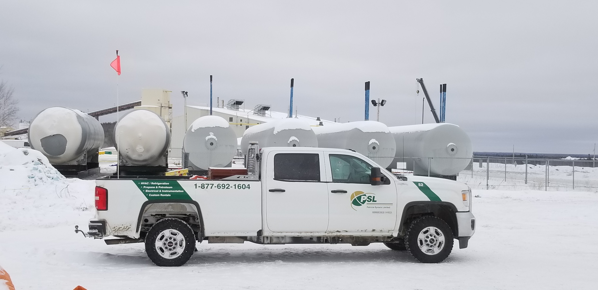 fossil fuel industry white truck on a mine site in front of propane tanks