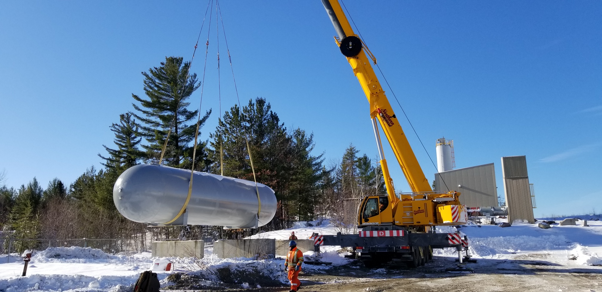 bulk plant propane being installed and a crane holding it
